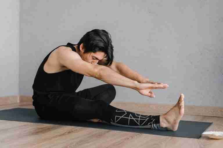 Adult man stretching on a mat in a calm indoor setting, promoting fitness and relaxation.