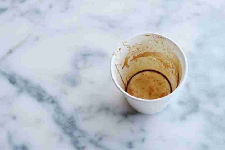 An overhead view of an empty coffee cup on a marble background, showcasing texture and detail.