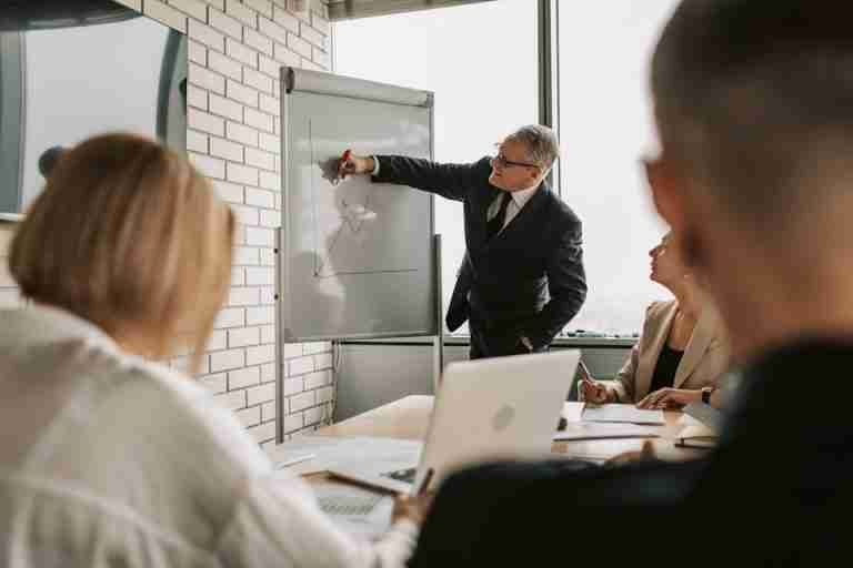 A focused business team engaging in a meeting with a presentation on a whiteboard.