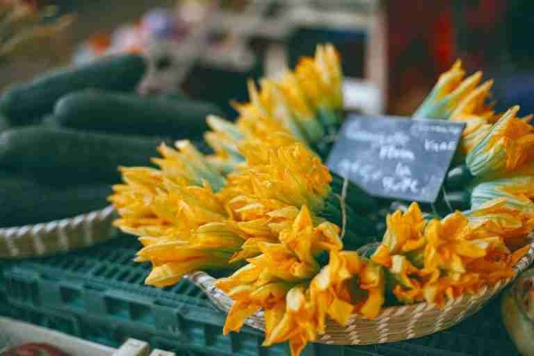 High angle of zucchini flowers in basket near cucumbers selling at food bazaar