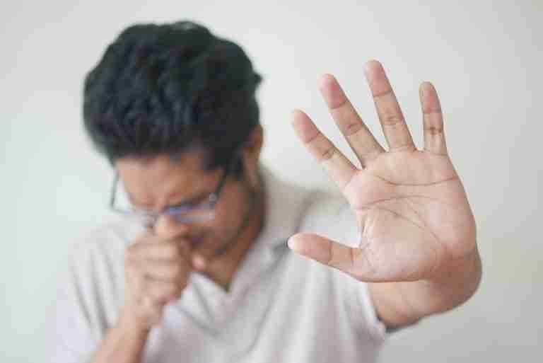 Unwell man covering cough with hand, showing sign of illness