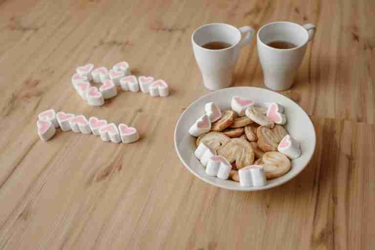 Heart-shaped cookies and tea cups on a wooden table, perfect for a cozy snack.