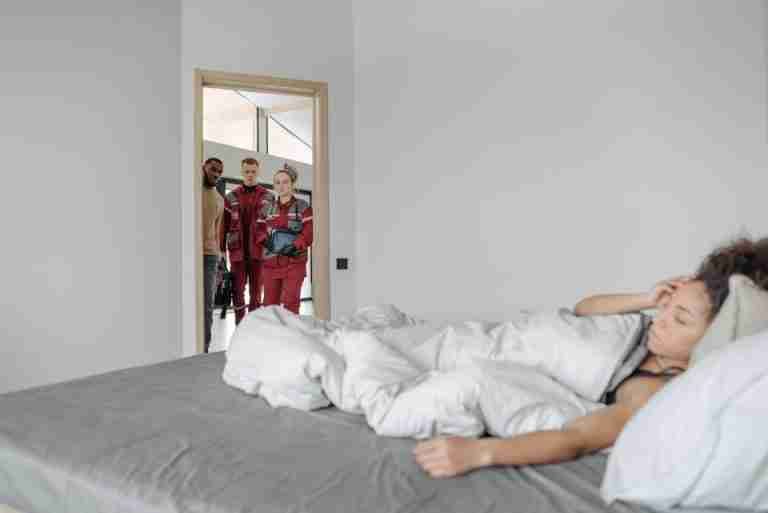 Medical professionals attending to a sick woman in her home, offering urgent healthcare support.