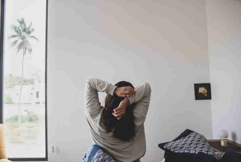 A woman stretching in a modern bedroom with morning light, offering a sense of relaxation and tranquility.