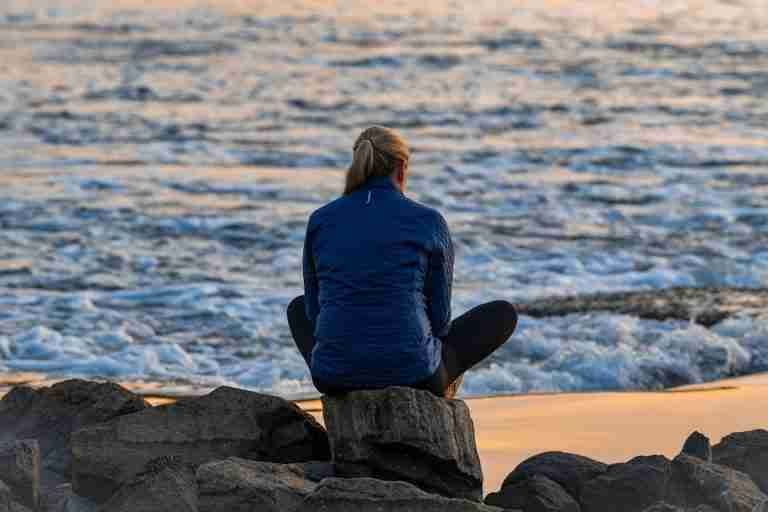 Peaceful morning scene of a person sitting by the coastal waters at sunrise in Stamford, Connecticut.