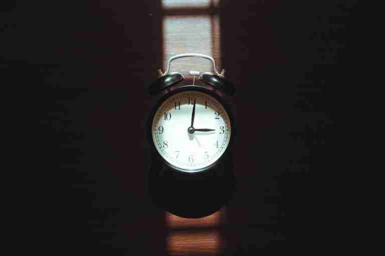 Classic vintage alarm clock with dramatic light and shadow play, evoking nostalgia and warmth.