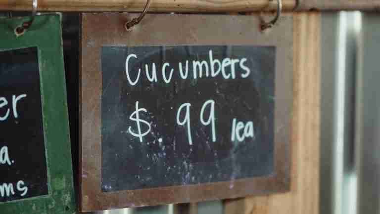 Close-up of a chalkboard sign showing cucumbers priced at 99 cents each.