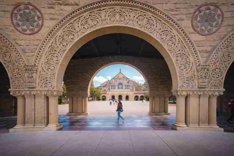Intricate stone arches at Stanford University framing the scenic campus view.