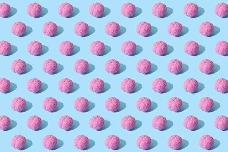 Creative composition of pink brain models in a repeating pattern on a light blue surface, showcasing abstract thinking.