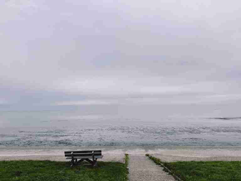 Peaceful coastal scene with an empty bench facing the calm sea.