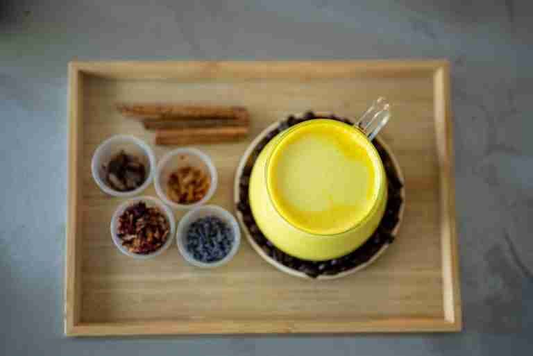 A top-down view of a turmeric latte surrounded by diverse spices for an aromatic experience.