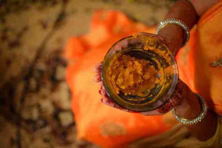 Close-up of a woman's hands holding a bowl of turmeric, showcasing Indian tradition.