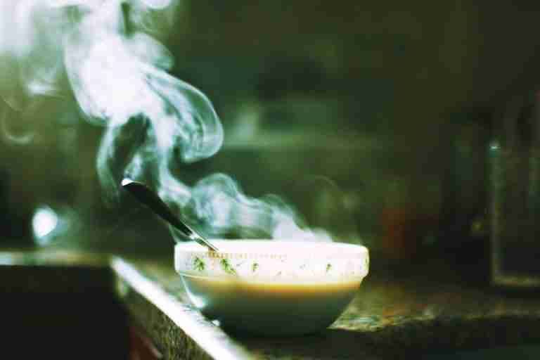 A steaming bowl of soup sits on a kitchen counter, emitting warm wafts into the air.