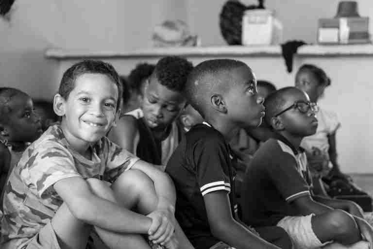 Black and white photo of attentive children sitting in a classroom, listening intently.