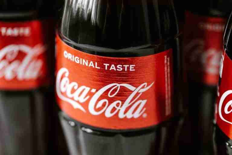 Set of glass bottles of refreshing cold coke with red sticker placed close to each other