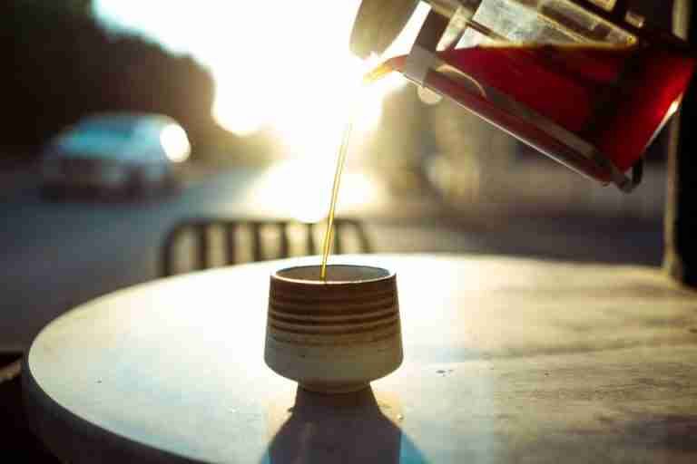 Warm morning light as coffee is poured into a cup at an outdoor cafe table in Baghdad.