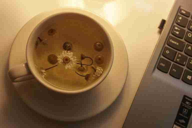 A soothing cup of chamomile tea next to a laptop, perfect for relaxation or work breaks.