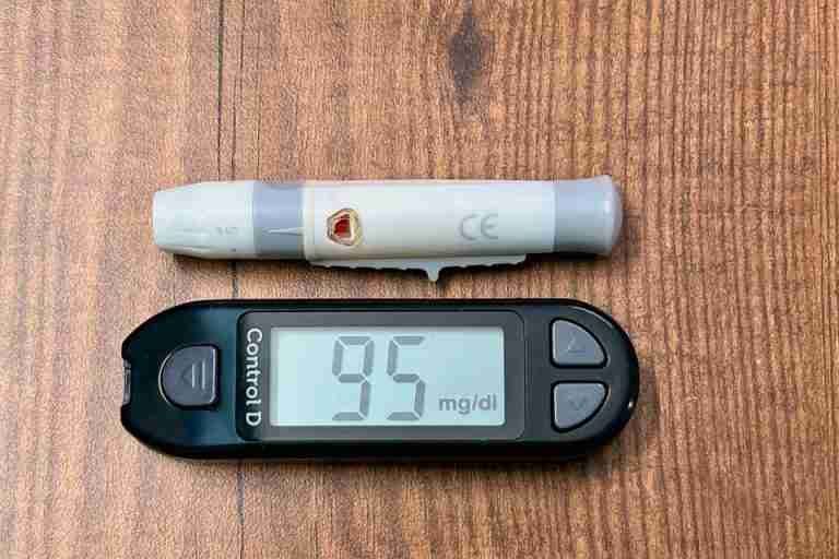 Close-up of a glucometer reading 95 mg/dl with a lancing device, ideal for diabetes and healthcare imagery.