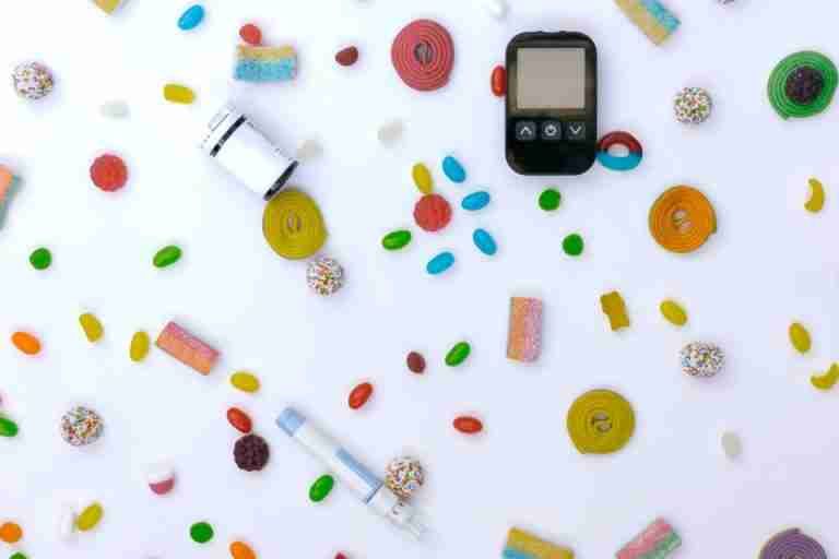 Scattered candies with glucose meter and syringe indicating diabetes and healthcare.