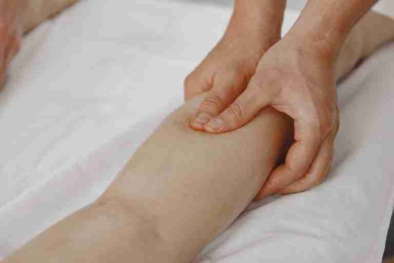 Close-up image of a massage therapist applying pressure on a client's leg for muscle relaxation.