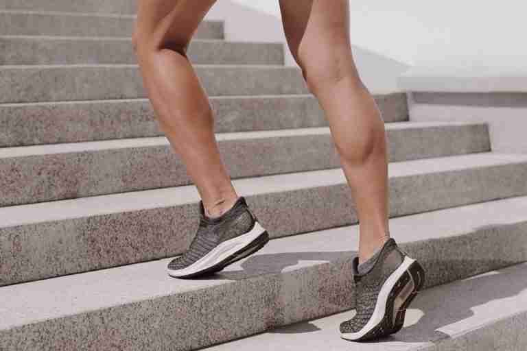 Close-up of an athlete in sneakers climbing outdoor stairs, showcasing toned muscles.