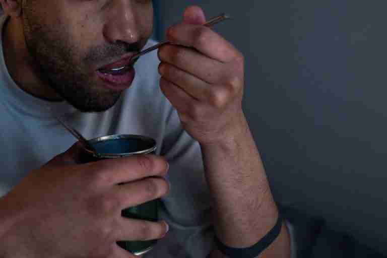 Close-up of a man eating canned food at home, highlighting quarantine lifestyle during isolation.